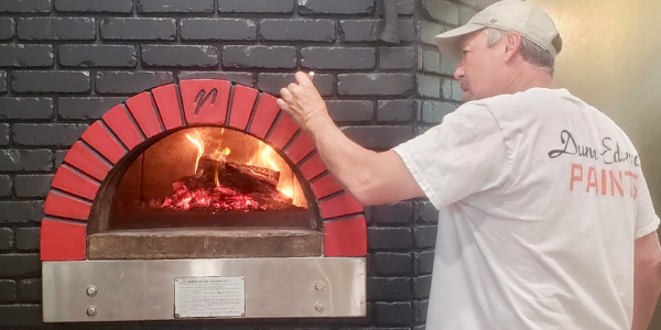 Image of Tony Rosa painting the exterior of the pizza oven at Craft Roots